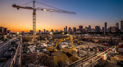 Excavator and crane working on a building foundation at sunset